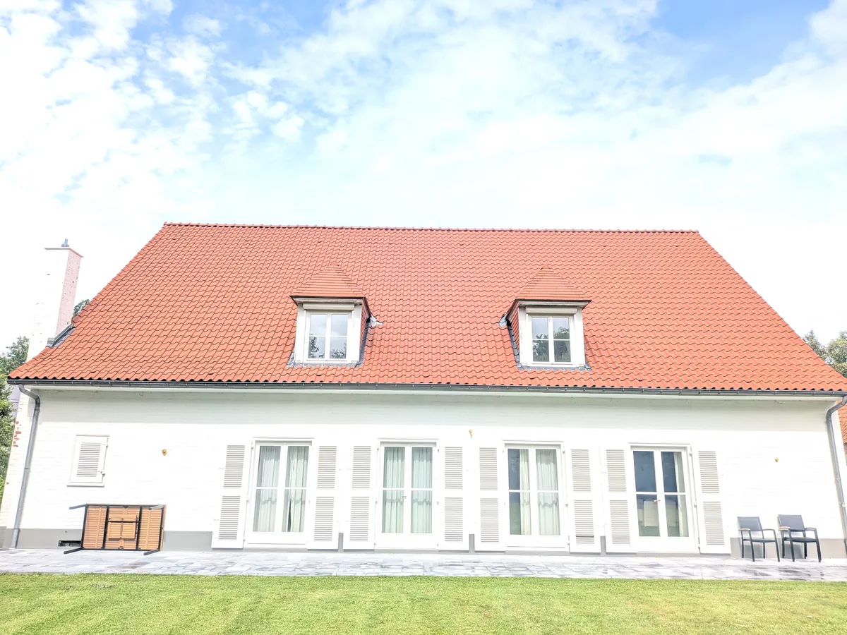 Toiture en tuiles rouges avec deux lucarnes sur une maison blanche