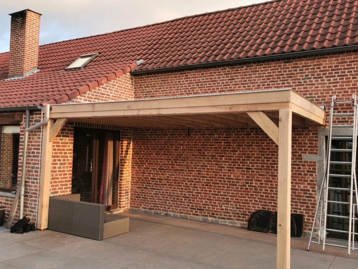 Auvent en bois construit contre la façade d'une maison en brique