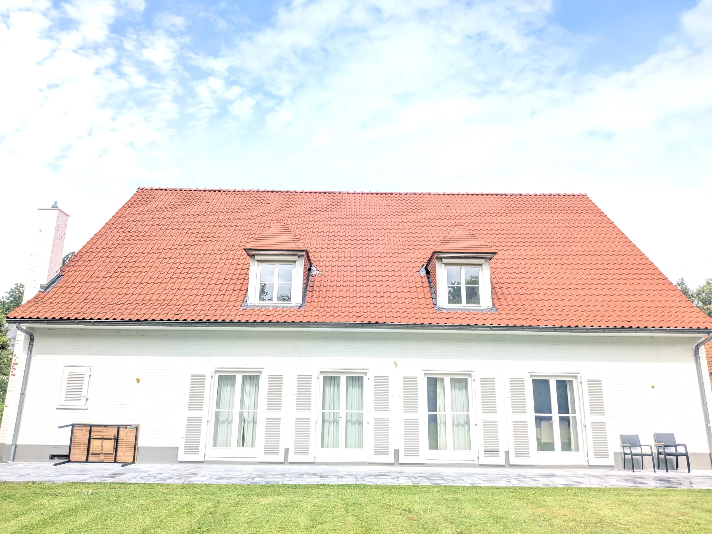 Toiture en tuiles rouges avec deux lucarnes sur une maison blanche